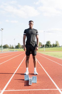 Athlete standing in front of starting line at stadium