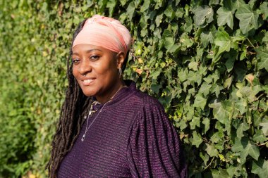 Sarmaşık duvarının önünde rastalı güzel bir kadının portresi.