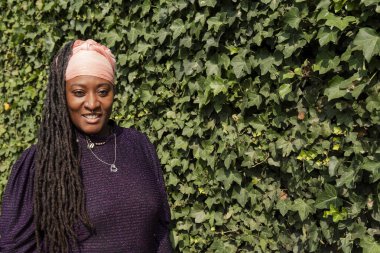 Sarmaşık duvarının önünde rastalı güzel bir kadının portresi.