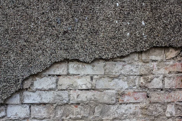 a brick wall with half-fallen plaster