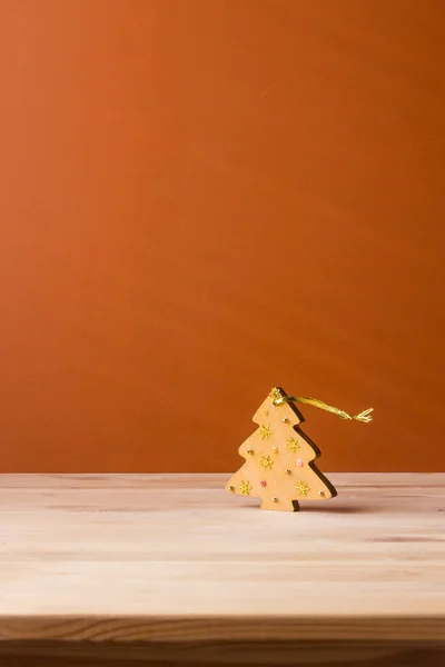 Mainan Natal berupa pohon Natal dari kayu, berdiri di atas meja berwarna krem dengan latar belakang oranye — Stok Foto