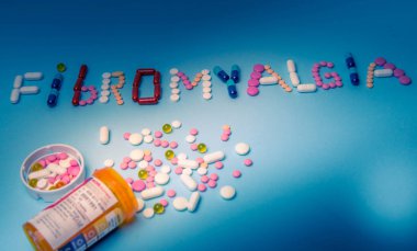  The word Fibromyalgia written by colorful medicines, pills, drugs, tablets, capsules, with purple butterfly on a blue background clipart
