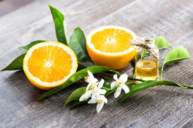 Juicy Orange cut in two parts and neroli, flowers of orange tree, on rustic wood background. The Orange blossom is the fragrant flower of the Citrus is used in perfume and tea, aphrodisiac. clipart