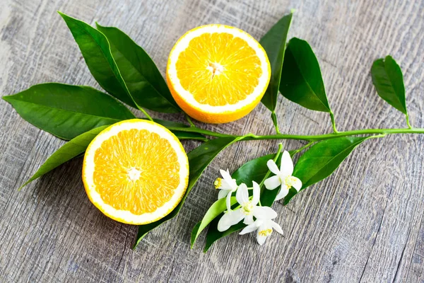 多汁的橙切成两部分和内罗利 橙树的花朵 在质朴的木材背景 橙花是柑橘的芬芳花用于香水和茶 壮阳药 — 图库照片