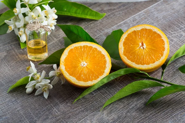 Juicy Orange cut in two parts and neroli, flowers of orange tree, on rustic wood background. The Orange blossom is the fragrant flower of the Citrus is used in perfume and tea, aphrodisiac.