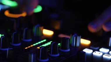 DJ elleri gece konsolda renkli kulüp ışıklarıyla karışıyor. Parti hayatı, gençler eğleniyor..