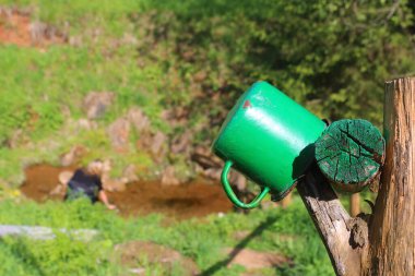 Çitte yeşil metal bardak var.