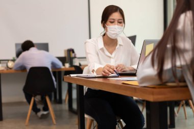 Asyalı iş kadınları iş hakkında konuşur ve maske takarlar. Yeni nomal..