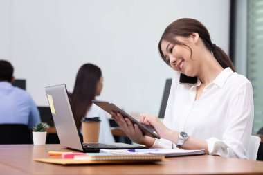 Asyalı iş adamı ve kadın ofiste konuşur ve işi kağıda döker.