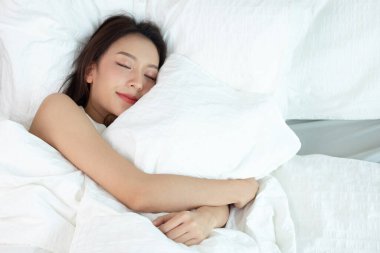Beyaz yatakta uyuyan Asyalı kadınlar ve tatlı rüyalar.