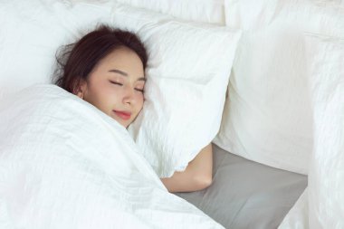 Beyaz yatakta uyuyan Asyalı kadınlar ve tatlı rüyalar.