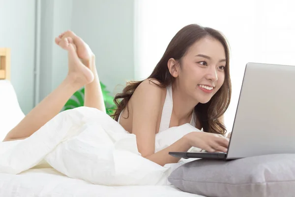 집안의 침대에 앉아서 랩탑으로 일하는 아시아 — 스톡 사진