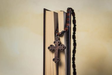 Din kavramı. Hristiyan dini. Tahta bir zincirde tahta haç. İncil 'in sayfaları arasında bir haç yatar. Eski bir gazetenin arka planında fotoğraf. Yan resim