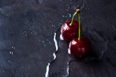 Siyah arka planda kiraz. İki kiraz suyun üzerinde duruyor..