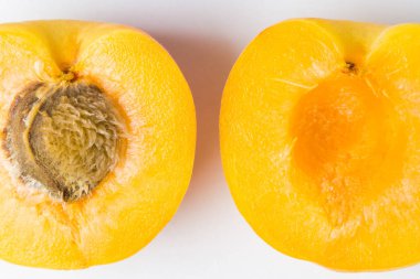 Beyaz arka planda iki dilim kayısı. Bir dilim kayısı ve bir taş. Fotoğraf yukarıda.