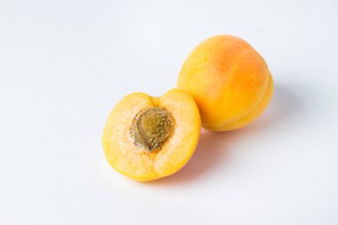 Beyaz arka planda kayısılar. Yanında kayısı ve kayısı olan yarım bir kayısı.