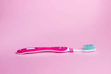 Pembe arka planda diş fırçası. Diş fırçası yüzeyde yatıyor. Ağız temizliği.