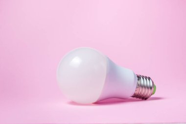 Pembe arka planda beyaz ampul. Ampul yüzeyde duruyor.