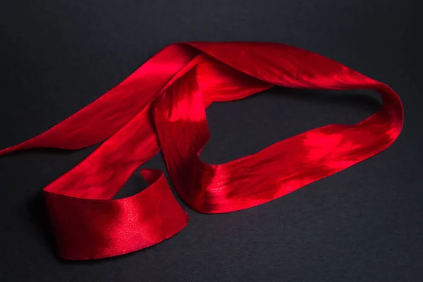黑色背景上的红丝带带子在一个黑色的表面上 — 图库照片