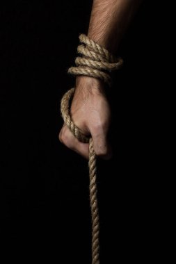 Male hand holds a rope on a black background. Jute rope wraps around the arm. clipart