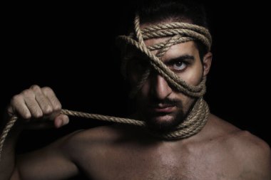 Adamın yüzü ipe sarılmış. El ipi çeker, düğümü sıkarak. Bir adamın yaratıcı portresi. Kendine güvenen bir bakış..