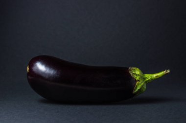 Siyah arka planda patlıcan. Çerçevenin ortasında taze bir patlıcan var..