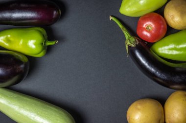 Siyah arka planda sebzeler. Siyah arka planda çeşitli taze sebzeler var. Yukarıdan çekilmiş bir fotoğraf. Ortada bir yazı ya da logo için bir yer var.