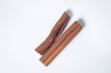 Beyaz arka planda tarçın. İki tarçın çubuğu, biri diğerinin yanında..