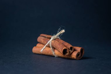 Siyah arka planda tarçın. İki çubuk tarçın jüt ipliğiyle bağlanmış.