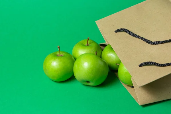 绿色的苹果 绿色的背景 苹果从纸袋里掉了出来 — 图库照片