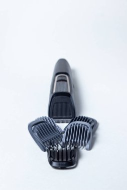 Beyaz arka planda sakal kesicisi. Farklı boyutlarda eklentiler budayıcının yanına yerleştirilir. Sakal bakımı. Erkek stili