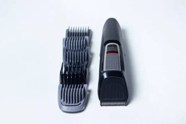 Beard trimmer on a white background. Different sized attachments are placed next to the trimmer. Beard care. Male style