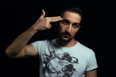 Tabanca şeklinde ver. Adam elini kafasına dayadı ve tabanca şeklini aldı. Fotoğraf siyah arkaplanda