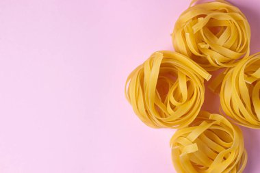 Pembe arka planda makarna yuvası. İtalyan makarnası. Makarna yuvaları yan yana uzanıyor. Avrupa mutfağı