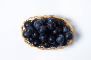 Hasır sepetteki erik. Beyaz arka planda fotoğraf. Yaz hasadı