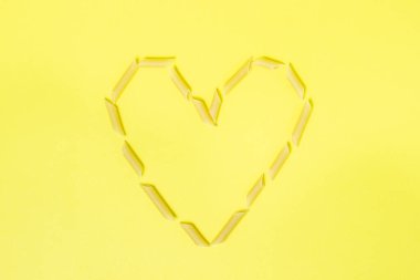 Makarna bir kalp şeklinde. Sarı arka planda makarna. Yukarıdan Fotoğraf