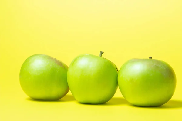 黄色背景上有三个绿色苹果 苹果排成一排 — 图库照片