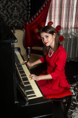 Kırmızı elbiseli kız. Kız piyano çalıyor. Zarif stil