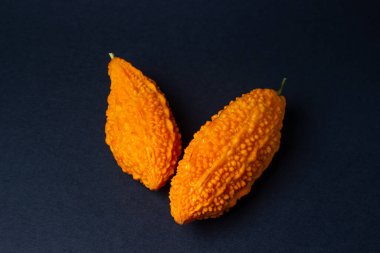 Siyah arka planda Momordica. Egzotik bir sebze. İki anne yan yana yatar.