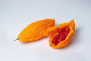 Beyaz arka planda Momordica. Egzotik bir sebze. Açılan momordika, kırmızı tohumların içinde