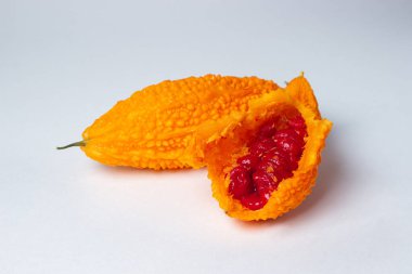 Beyaz arka planda Momordica. Egzotik bir sebze. Açılan momordika, kırmızı tohumların içinde