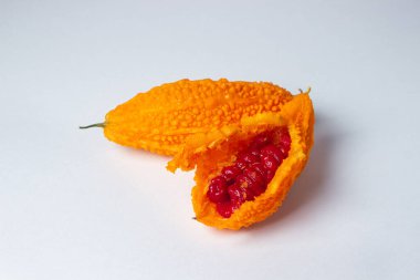 Beyaz arka planda Momordica. Egzotik bir sebze. Açılan momordika, kırmızı tohumların içinde