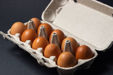 Siyah arka planda yumurtalar. Karton kutuda tavuk yumurtası.