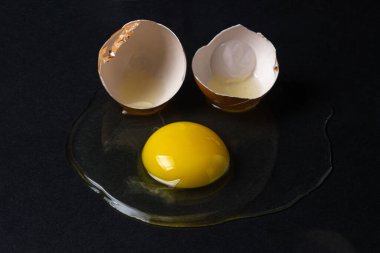 Siyah arka planda yumurta. Kırık tavuk yumurtası. Yumurta sarısı masaya döküldü.