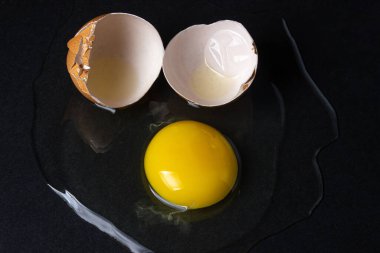 Siyah arka planda yumurta. Kırık tavuk yumurtası. Yumurta sarısı masaya döküldü.