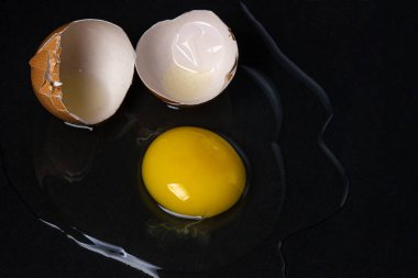Siyah arka planda yumurta. Kırık tavuk yumurtası. Yumurta sarısı masaya döküldü.