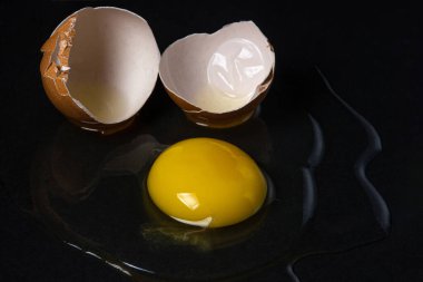 Siyah arka planda yumurta. Kırık tavuk yumurtası. Yumurta sarısı masaya döküldü.