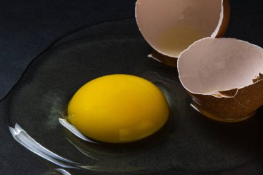 Siyah arka planda yumurta. Kırık tavuk yumurtası. Yumurta sarısı masaya döküldü.