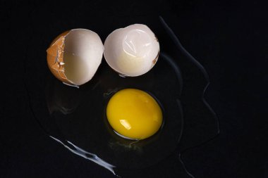 Siyah arka planda yumurta. Kırık tavuk yumurtası. Yumurta sarısı masaya döküldü.