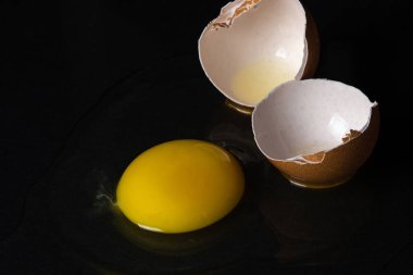 Siyah arka planda yumurta. Kırık tavuk yumurtası. Yumurta sarısı masaya döküldü.
